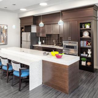 A modern kitchen with dark wood cabinets, a white island, and stainless steel appliances.