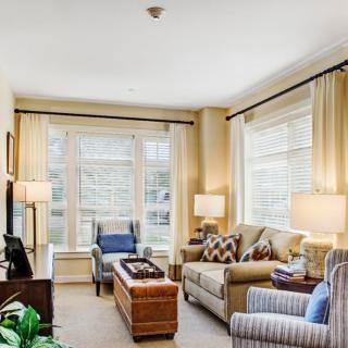 A cozy and well-lit living room with comfortable seating and large windows.