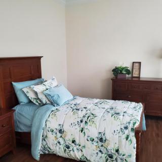 A cozy bedroom with a single bed featuring floral bedding and wooden furniture.