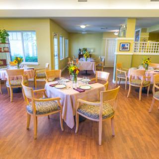 A well-lit dining area with neatly arranged tables and chairs, featuring wooden floors and decorative elements.