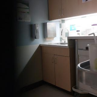 A dimly lit corner of a hospital room featuring a countertop with medical supplies.