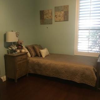 A cozy bedroom with a single bed, nightstand, and window with shutters.