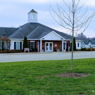 A charming community center with a classic architectural design, set against a serene landscape.