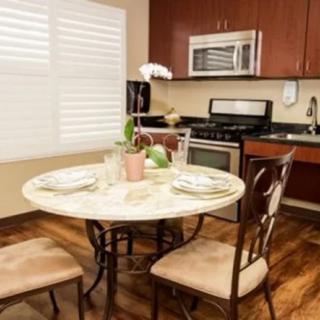 A cozy kitchen with a small dining area, featuring a marble table and wooden chairs.