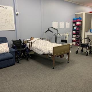 A well-equipped patient room featuring a hospital bed, wheelchairs, and nursing supplies.
