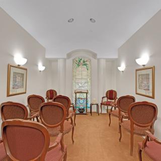 A small, elegantly decorated room with arranged chairs and wall-mounted lights.