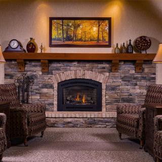 A cozy living room with a stone fireplace and comfortable armchairs.