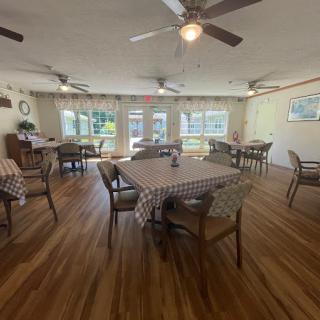 A cozy dining room with checkered tablecloths and ceiling fans, illuminated by natural light.