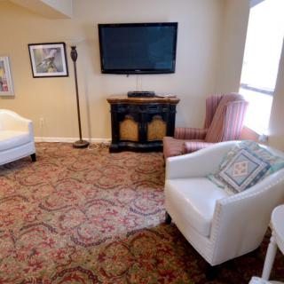 A cozy living room with comfortable seating, a TV, and a decorative carpet.
