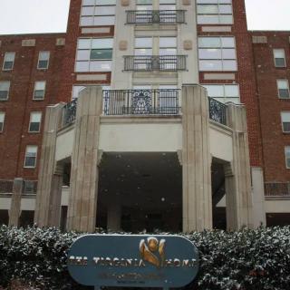 Entrance of a multi-story apartment building with signage in front.