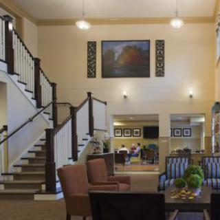 A spacious lobby featuring a staircase, comfortable seating, and elegant decor.