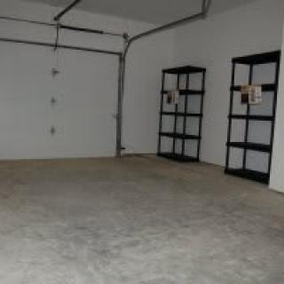 An empty garage with shelves and a concrete floor.
