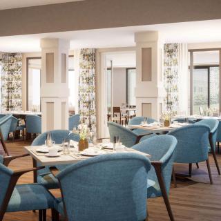 A modern restaurant interior with blue upholstered chairs and neatly arranged tables.
