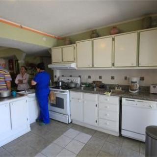 People cooking in a home kitchen with white cabinets and modern appliances.