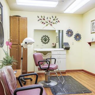 A cozy hair salon interior featuring chairs, a mirror, and decorative wall art.
