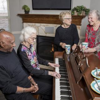 A group of seniors enjoying a music session and conversation at home.