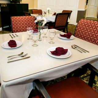 A neatly set dining table with red-patterned chairs and folded napkins in a restaurant setting.