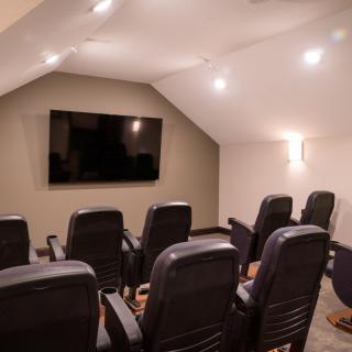 A cozy home theater room with multiple seats facing a large television screen.