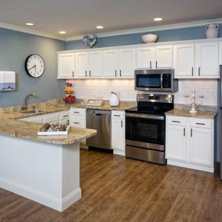 A modern kitchen with white cabinetry, stainless steel appliances, and hardwood flooring.