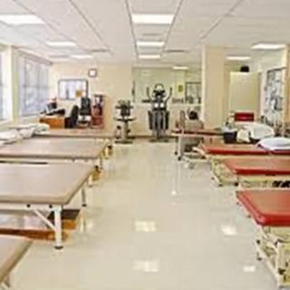 A spacious physical therapy clinic with several treatment tables and exercise equipment.
