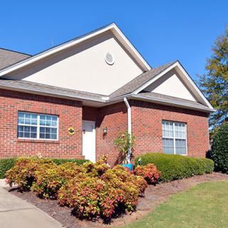 A suburban brick house with well-maintained landscaping and a clear blue sky.