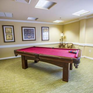 A cozy gaming room with a red-felt billiards table and stylish decor.