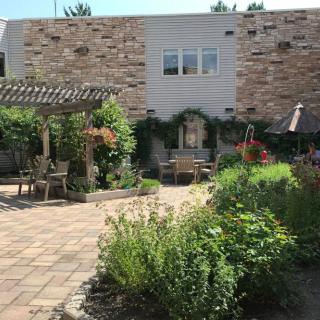 A tranquil garden patio with a pergola, surrounded by lush greenery and outdoor seating.