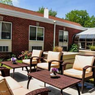 A sunny patio area with comfortable seating and a brick building in the background.