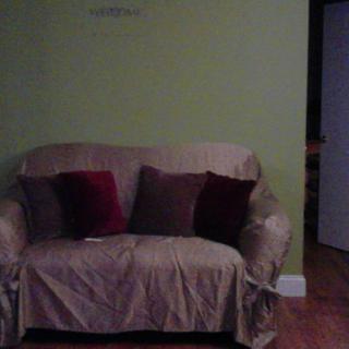 A cozy living room with a couch covered by a slipcover and decorated with pillows.