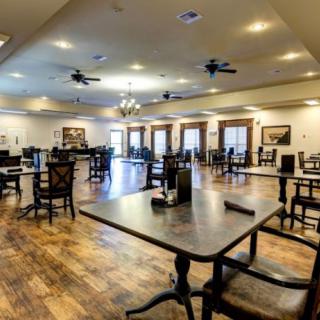 A spacious dining room with wooden floors and well-arranged tables and chairs.