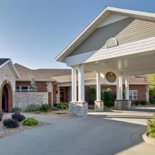 A well-maintained building entrance with a covered driveway and landscaped surroundings.