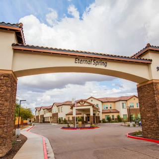 A residential building with a prominent archway entrance under a cloudy sky.