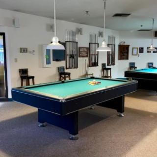 A spacious game room featuring pool tables and overhead lighting.