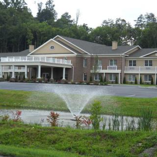 A scenic view of a large building with a fountain in the foreground, surrounded by greenery.