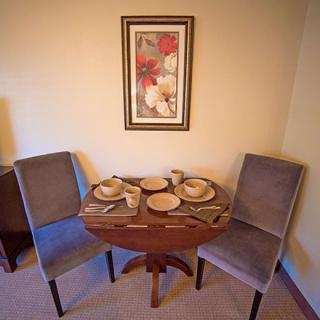 A cozy dining nook with a round table set for two and artwork on the wall.