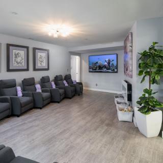 A modern home theater room with comfortable seating and a large screen TV.