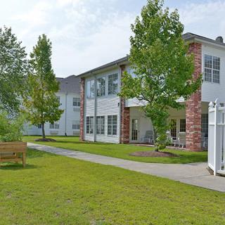 A modern residential building with a well-maintained lawn and surrounding trees.