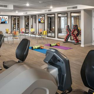 A gym with various exercise equipment, including stationary bikes, treadmills, and yoga mats, set up for workout sessions.
