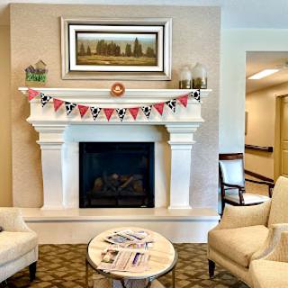 A cozy living room featuring a stylish fireplace adorned with decorative banners and comfortable seating.