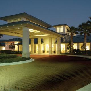 A well-lit building entrance at night with palm trees and modern architecture.
