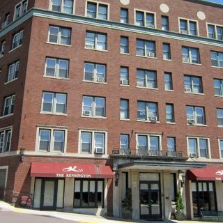 A historical brick building with multiple windows and red awnings.
