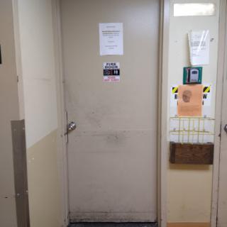 A view of a door in a hallway with various notices attached.