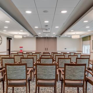 An empty conference room with rows of chairs facing a stage or presentation area.