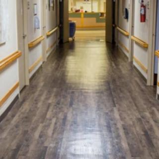 A clean and well-lit hospital corridor with wooden flooring.