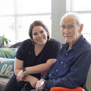 A caregiver and an elderly person sitting together indoors, sharing a moment of companionship.