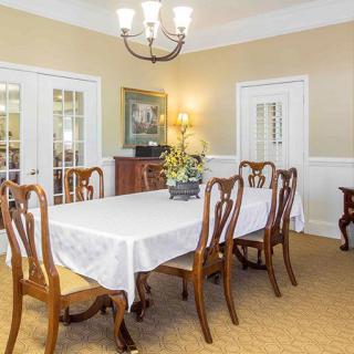 A classic dining room with a wooden table and chairs under a chandelier.