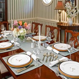 A beautifully set dining table with elegant dinnerware and floral centerpiece.