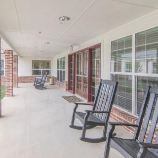 A spacious covered porch with rocking chairs and large windows.