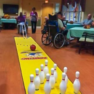 Seniors enjoying a game of indoor bowling in a nursing home.