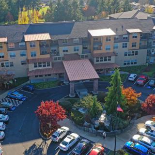 Aerial view of a building with a parking lot surrounded by colorful autumn trees.
